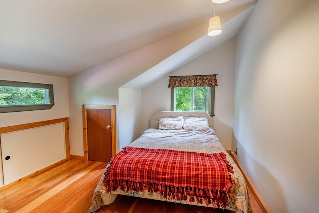 bedroom featuring lofted ceiling, baseboards, and wood finished floors