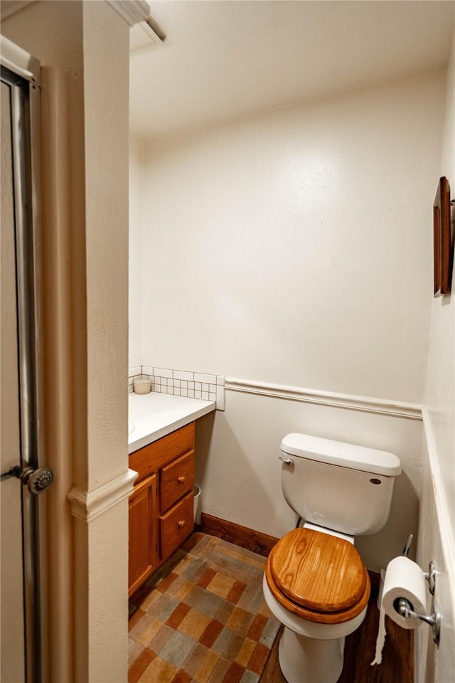 half bathroom with baseboards, vanity, and toilet