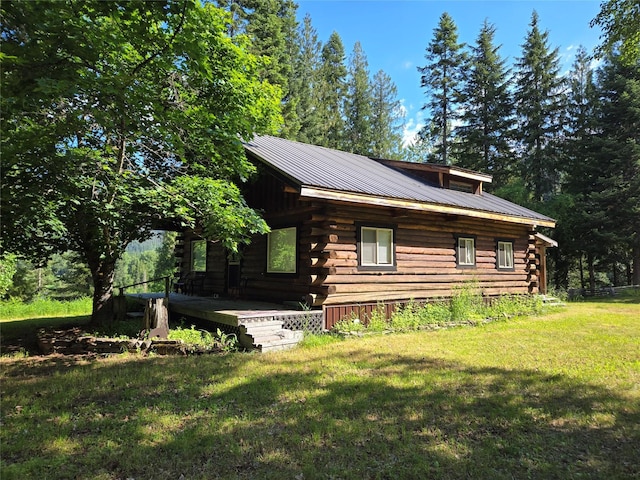 view of front facade with metal roof, a front lawn, log exterior, and a wooden deck