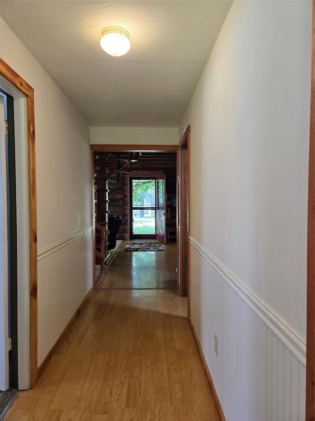 corridor featuring a wainscoted wall and light wood-style floors