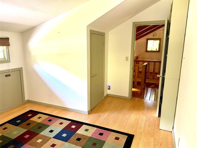 bonus room featuring light wood finished floors, baseboards, and vaulted ceiling