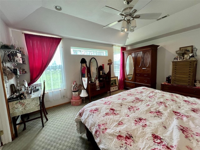 carpeted bedroom with ceiling fan and a raised ceiling