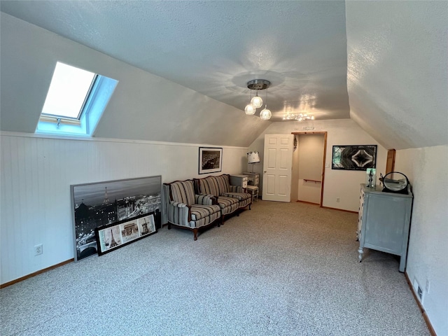 interior space featuring a textured ceiling, lofted ceiling with skylight, and carpet floors