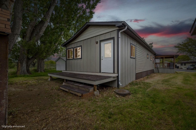 property exterior at dusk featuring an outbuilding and a lawn