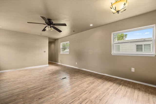 spare room with plenty of natural light, ceiling fan, and wood-type flooring