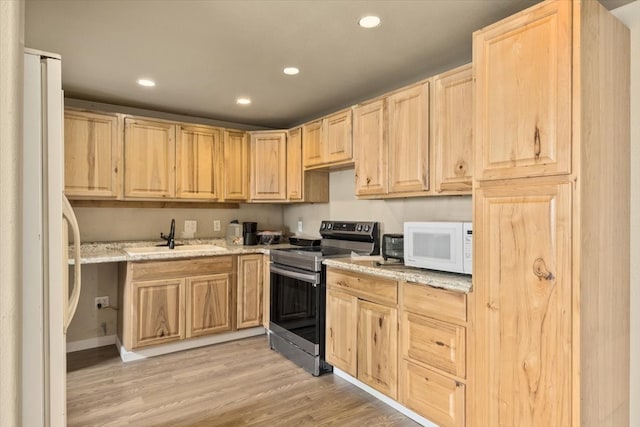 kitchen with white appliances, light hardwood / wood-style floors, light stone countertops, light brown cabinetry, and sink