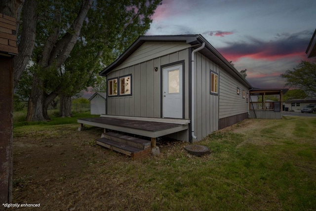 property exterior at dusk featuring an outdoor structure and a lawn