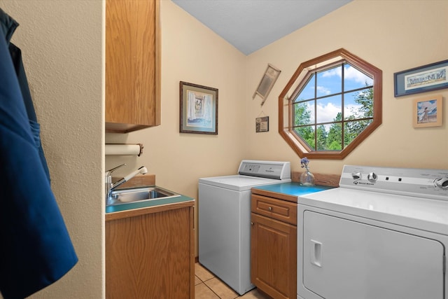 washroom with washing machine and dryer, sink, light tile patterned floors, and cabinets