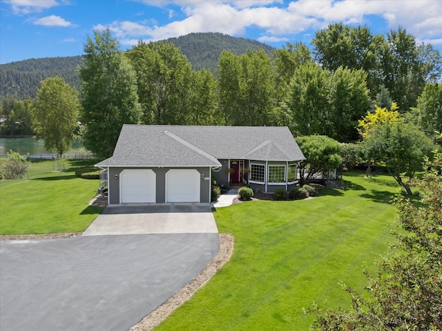 view of front of house featuring a mountain view, a front yard, and a garage