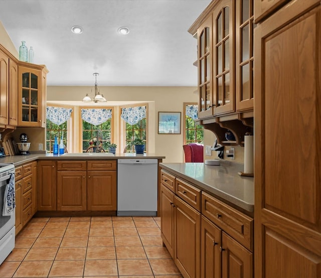 kitchen featuring pendant lighting, a healthy amount of sunlight, white appliances, and a notable chandelier