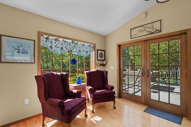 sitting room with french doors, lofted ceiling, and light hardwood / wood-style flooring