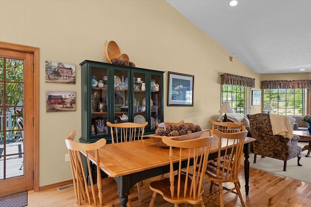 dining area with plenty of natural light, high vaulted ceiling, and light hardwood / wood-style flooring