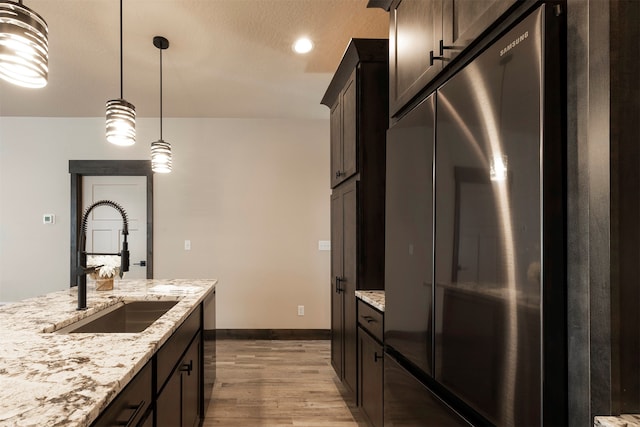 kitchen with dark brown cabinets, hanging light fixtures, sink, light hardwood / wood-style floors, and appliances with stainless steel finishes