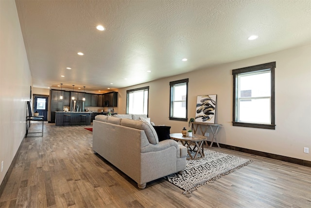 living room with light hardwood / wood-style floors, a textured ceiling, and plenty of natural light