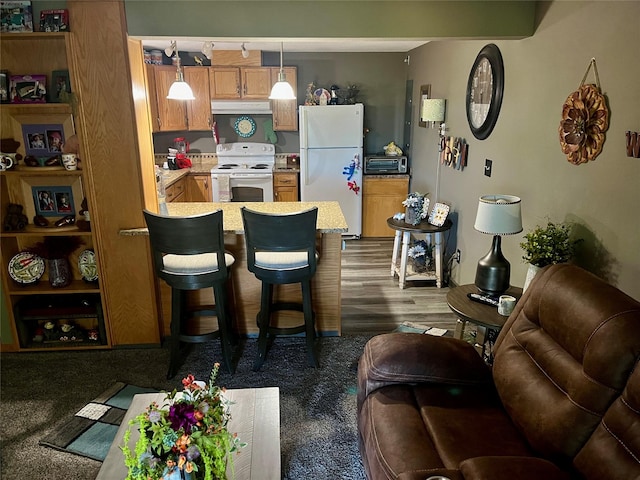 kitchen featuring a breakfast bar, pendant lighting, white appliances, and kitchen peninsula