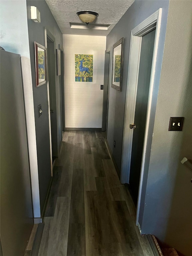 hallway with a textured ceiling and dark wood-type flooring