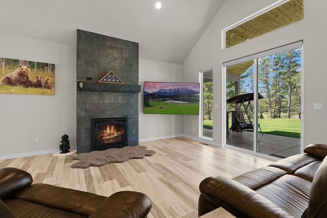 living room with light hardwood / wood-style floors, high vaulted ceiling, and a tile fireplace