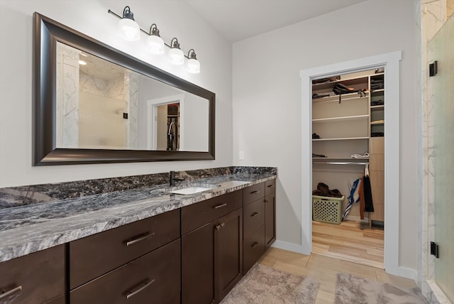 bathroom with a shower with shower door, wood-type flooring, and vanity