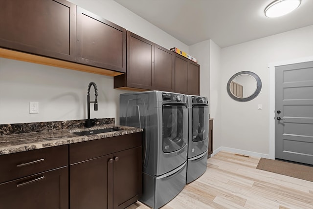 laundry room featuring washer and dryer, light hardwood / wood-style flooring, cabinets, and sink