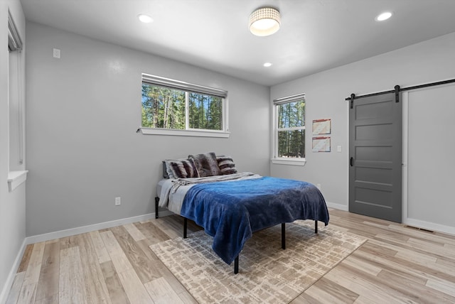 bedroom featuring light wood-type flooring and a barn door