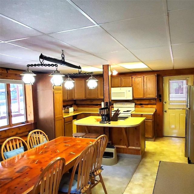 15426 Steamboat Dr, Augusta, MT 59410 - kitchen with light countertops, white appliances, a drop ceiling, a kitchen island, and brown cabinets
