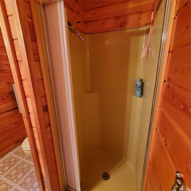 15426 Steamboat Dr, Augusta, MT 59410 - bathroom featuring toilet, tile patterned floors, a shower stall, and wood walls