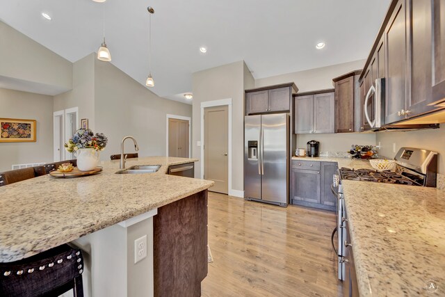 kitchen with pendant lighting, sink, a breakfast bar area, stainless steel appliances, and light stone countertops