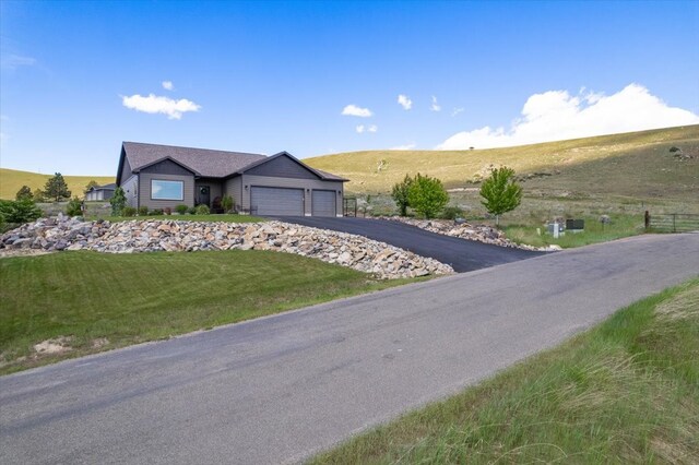 single story home with a garage, a rural view, and a front lawn