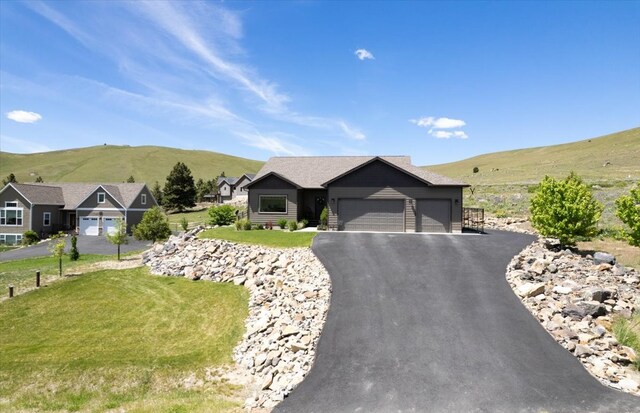 view of front of property featuring a garage, a mountain view, and a front lawn