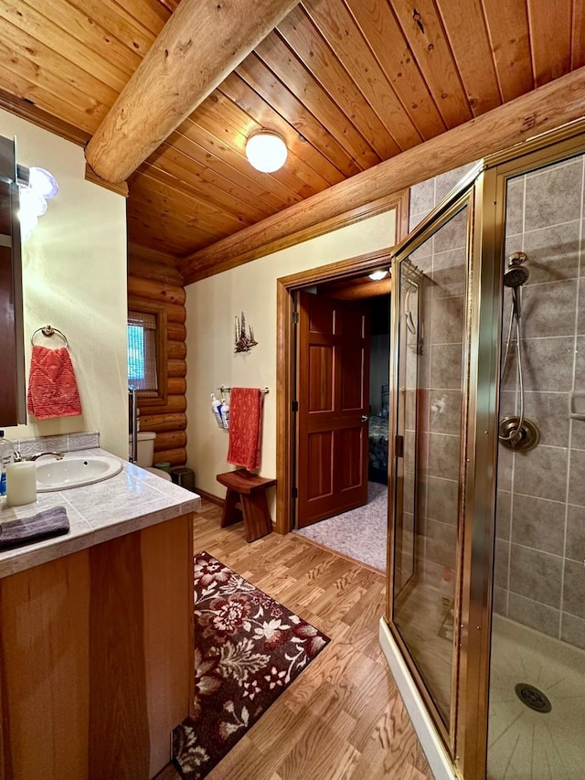 bathroom featuring vanity, hardwood / wood-style flooring, log walls, beamed ceiling, and an enclosed shower