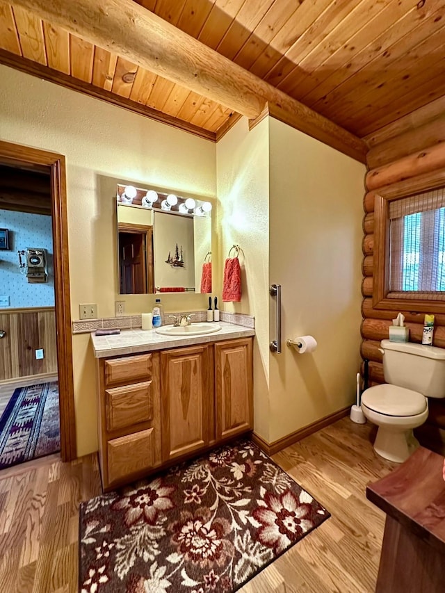 bathroom with rustic walls, vanity, wooden ceiling, hardwood / wood-style floors, and toilet