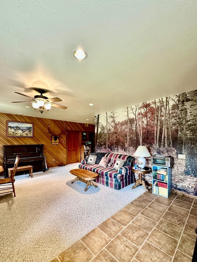 living room with a textured ceiling, ceiling fan, and wood walls