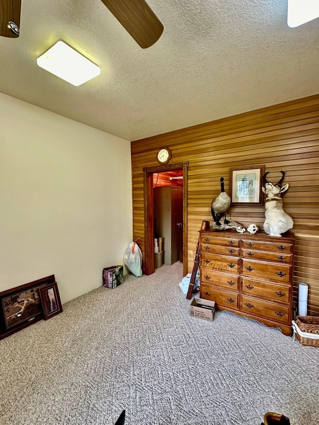 carpeted bedroom with a textured ceiling and wooden walls