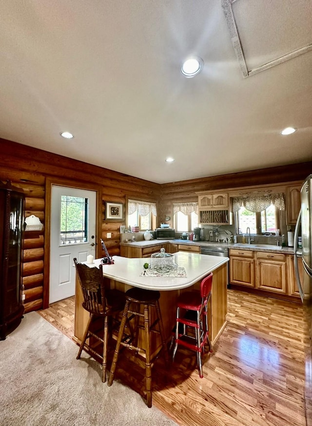 kitchen with a breakfast bar, a center island, log walls, and plenty of natural light