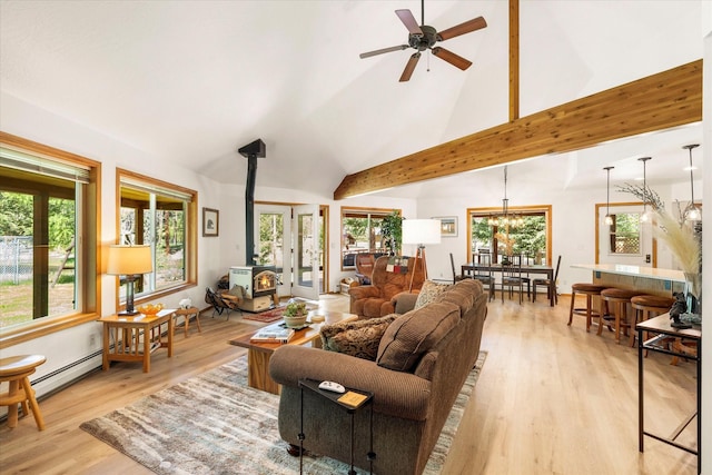 living room featuring a wood stove, ceiling fan with notable chandelier, light hardwood / wood-style flooring, vaulted ceiling with beams, and plenty of natural light