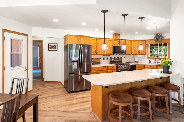 kitchen with kitchen peninsula, backsplash, stainless steel appliances, sink, and pendant lighting