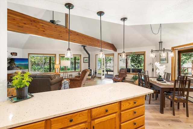 kitchen with light stone countertops, light hardwood / wood-style flooring, decorative light fixtures, and vaulted ceiling