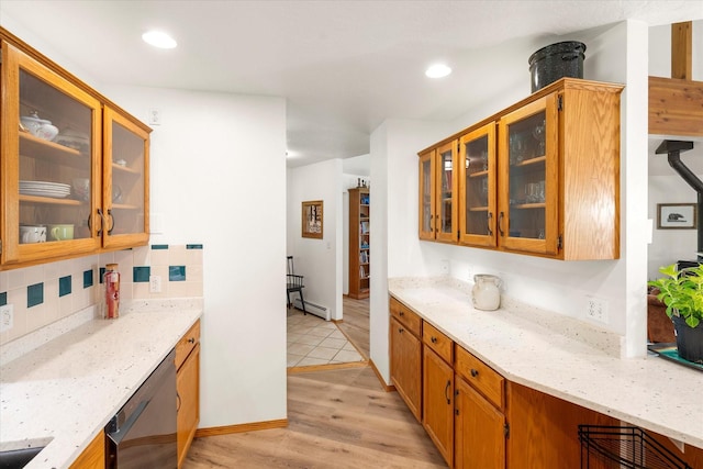 kitchen with baseboard heating, light stone counters, stainless steel dishwasher, backsplash, and light wood-type flooring