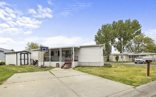 manufactured / mobile home with a shed, covered porch, and a front yard