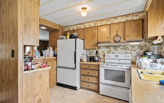 kitchen featuring tasteful backsplash, white appliances, and sink