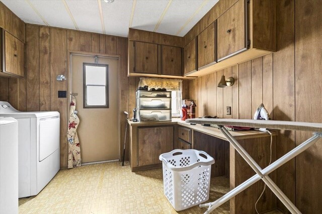 laundry room with washer / clothes dryer, wooden walls, cabinets, and light tile patterned floors