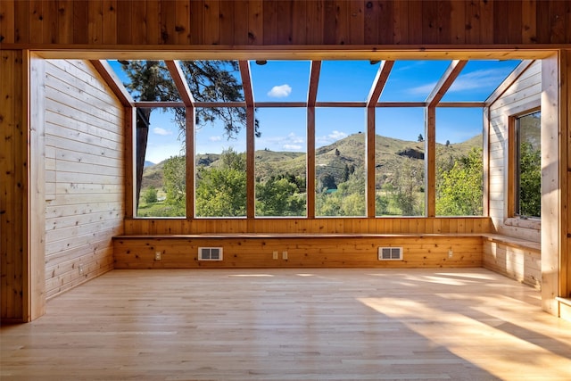 unfurnished sunroom with vaulted ceiling, plenty of natural light, and a mountain view