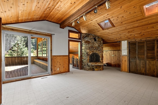 unfurnished living room featuring wood ceiling, track lighting, a fireplace, and lofted ceiling with skylight