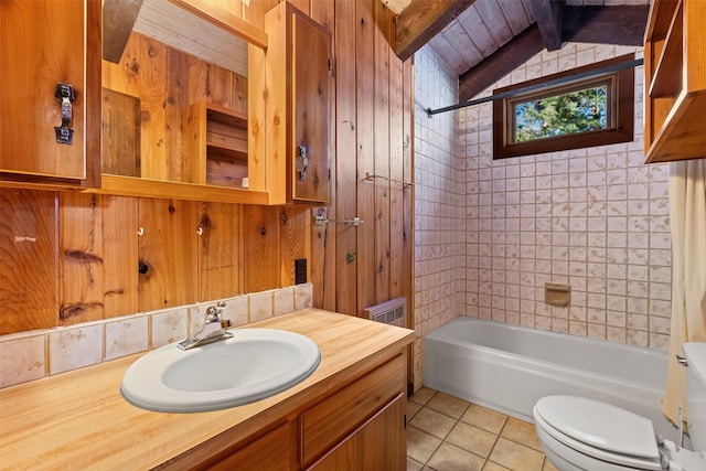 full bathroom with wood walls, toilet, tiled shower / bath combo, tile floors, and vaulted ceiling with beams