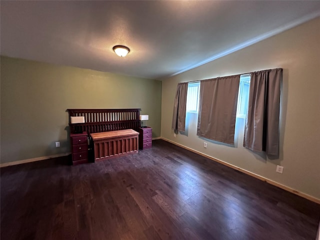 unfurnished bedroom with vaulted ceiling and dark wood-type flooring