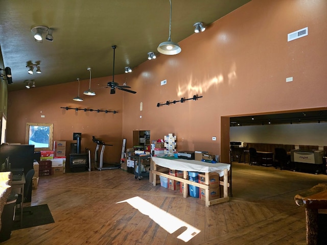 interior space with hardwood / wood-style floors, a towering ceiling, and ceiling fan