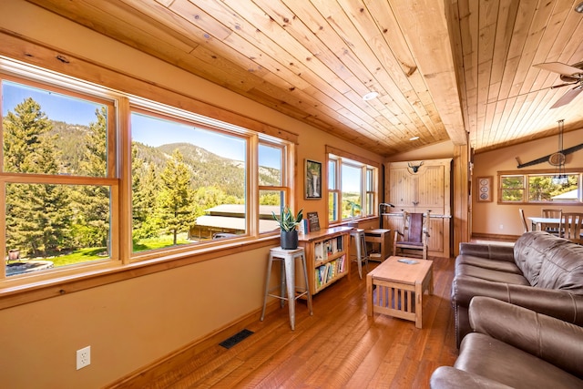 living area with lofted ceiling, visible vents, light wood-style flooring, a mountain view, and wooden ceiling