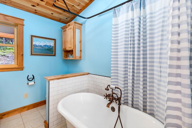 bathroom featuring tile patterned flooring, wooden ceiling, a freestanding bath, and baseboards