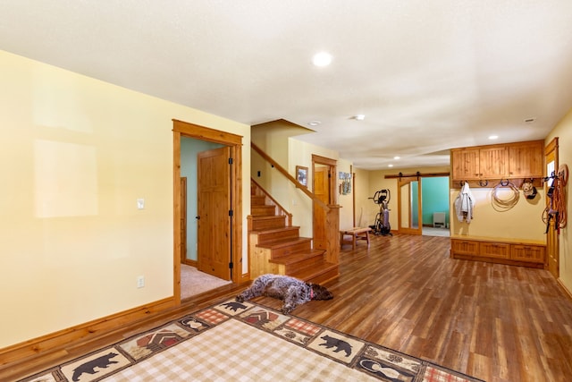 interior space featuring a barn door, recessed lighting, wood finished floors, baseboards, and stairs