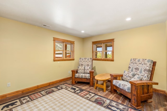 living area with plenty of natural light, wood finished floors, visible vents, and baseboards